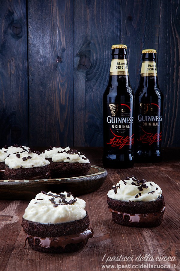 Tortine alla Guinnes ripiene di Nocciolata con glassa al mascarpone e panna con bottiglie sullo sfondo